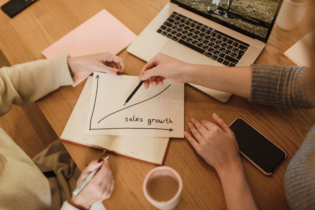 Two women reviewing a sales growth graph in an office